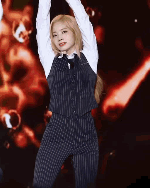 a woman in a striped vest and pants is dancing on a stage