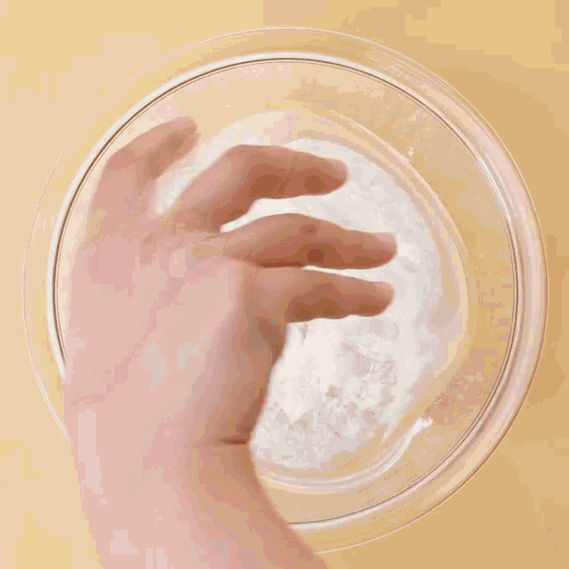 a person is cracking an egg into a bowl of flour