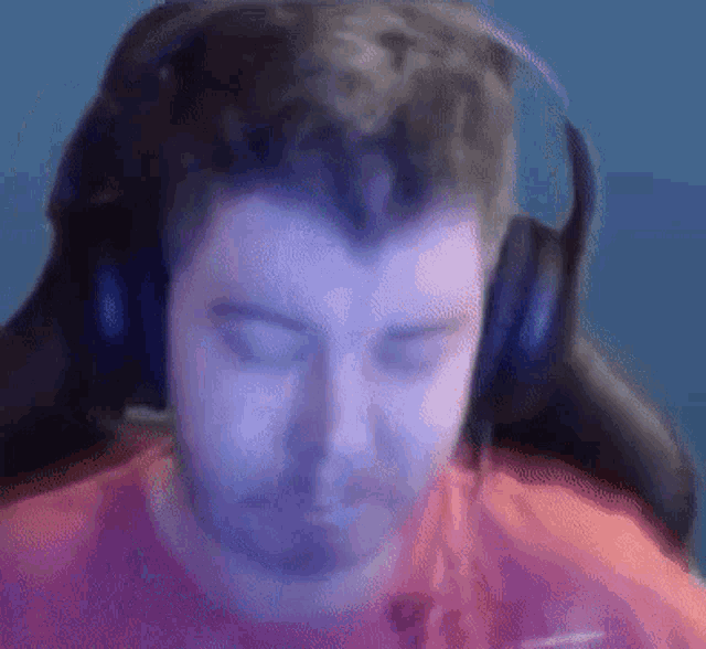 a man wearing headphones and a red shirt is sitting in a gaming chair .