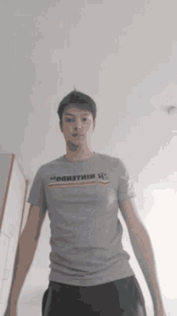 a man wearing a grey t-shirt that says " mooiatmiu " on it