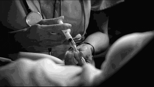 a black and white photo of a nurse holding a syringe in her hand