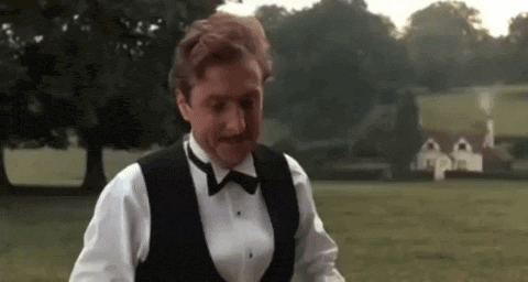 a man wearing a tuxedo and bow tie is standing in a field .