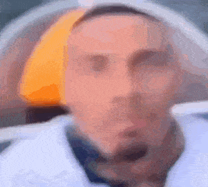 a blurry picture of a man 's face with a yellow hat .