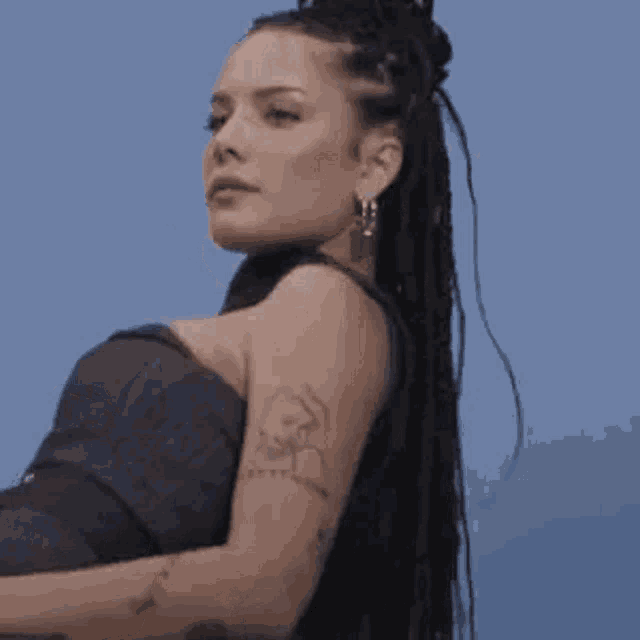 a woman with dreadlocks is wearing a black top and earrings .