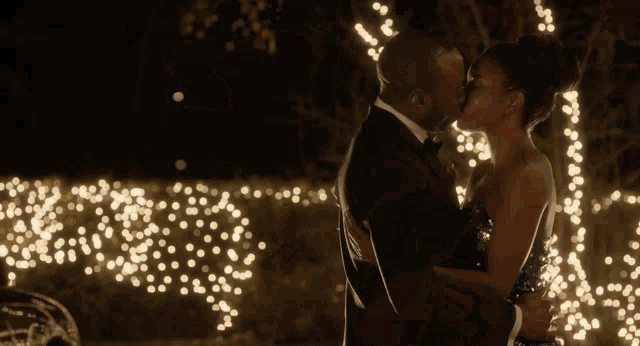 a man and woman are kissing in front of a christmas tree