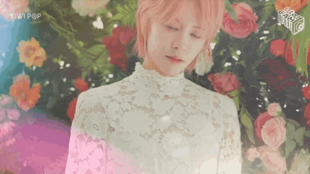 a woman in a white lace top is surrounded by flowers and the kiwi pop logo can be seen