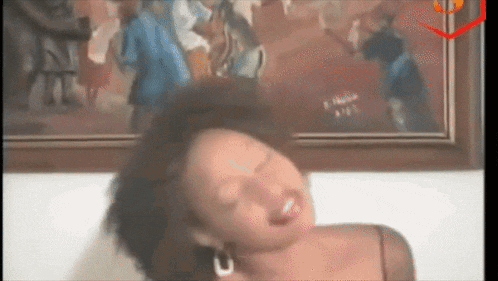 a woman is making a funny face in front of a painting on the wall .
