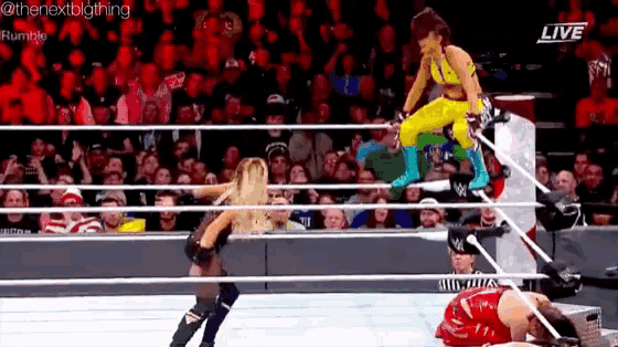 two women are wrestling in a wrestling ring while a crowd watches .
