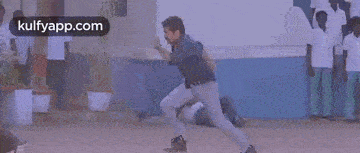 a group of men are running down a street in front of a building in a movie .