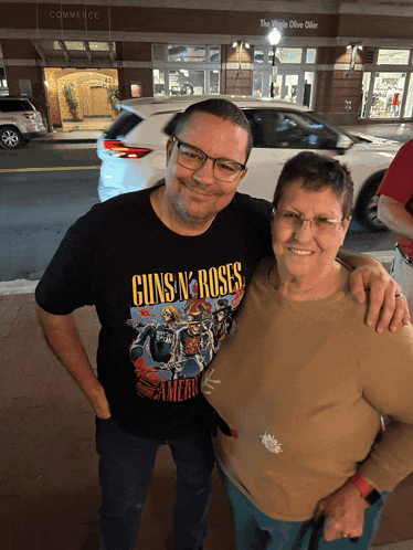 a man wearing a guns n ' roses t-shirt stands next to a woman