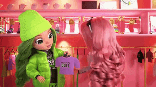 two dolls are standing next to each other in a store and one of them is holding a shirt that says doll on it .