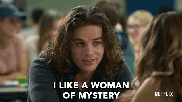 a man with long hair says " i like a woman of mystery " in front of a woman