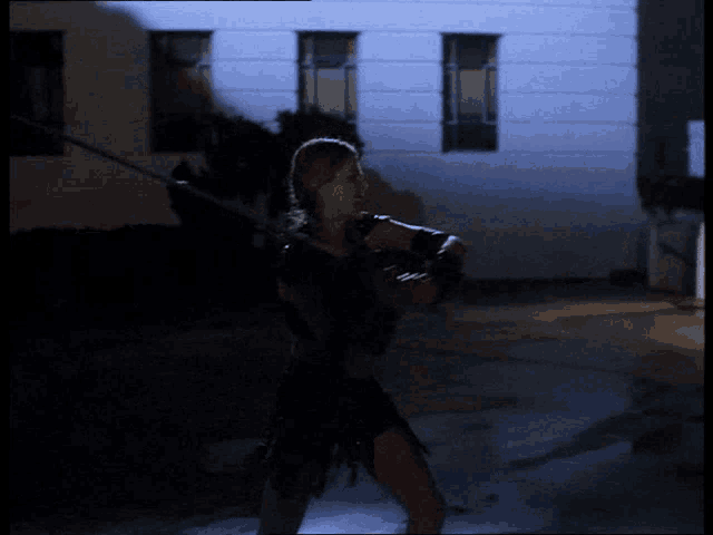 a woman is holding a sword in front of a building with the letter i on it