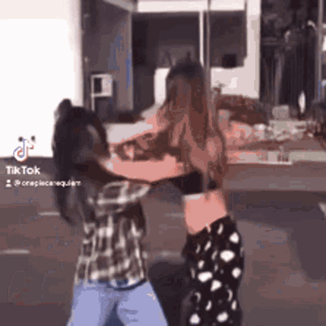 two women are standing next to each other on a street and fighting .