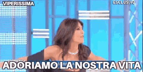 a woman is standing in front of a blue background with the words " adoriamo la nostra vita " on it .