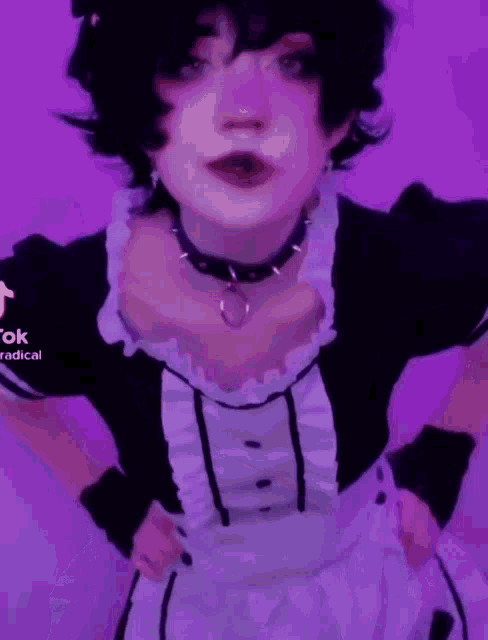 a person in a maid costume is standing in front of a purple wall .
