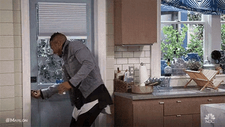 a man is standing in a kitchen holding a bottle of wine .