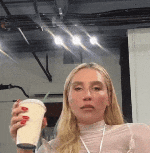 a woman with red nails is holding a cup in her right hand