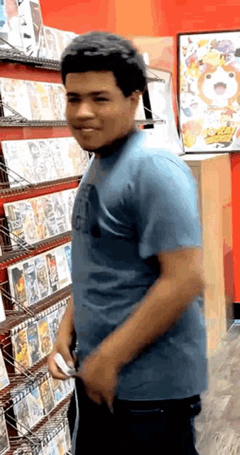 a man in a blue shirt is standing in front of a shelf full of video games