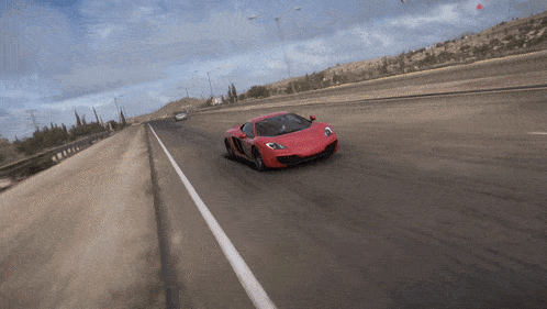 a red sports car is driving down a desert road