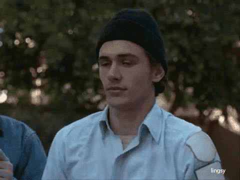 a man wearing a beanie and a blue shirt is looking at something