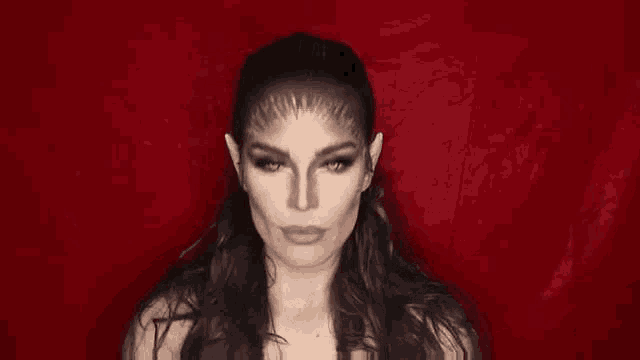 a woman with vampire makeup on her face is looking at the camera in a black and white photo .