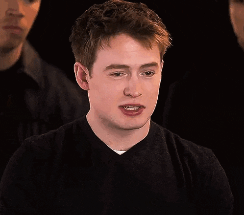 a young man in a black sweater is making a funny face .