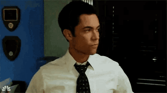 a man wearing a white shirt and tie is standing in front of a blue wall .