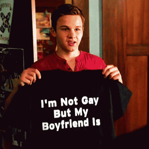 a young man is holding up a black shirt that says i 'm not gay but my boyfriend is