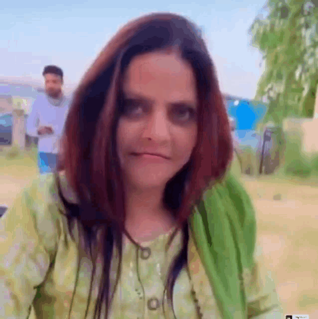 a woman in a green shirt is making a funny face