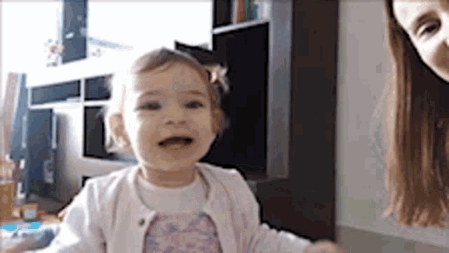 a little girl is sitting in front of a woman in a living room .