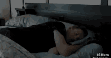 a man is laying in bed with a foreign language written on the bottom of the bed .