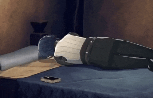 a person is laying on a bed with a book on the floor .