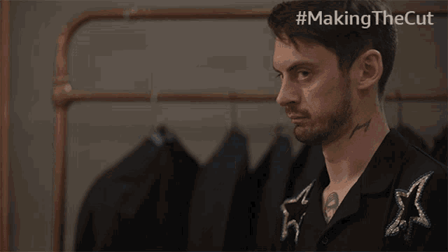 a man with a tattoo on his chest is standing in front of a rack of clothes with the hashtag #makingthecut