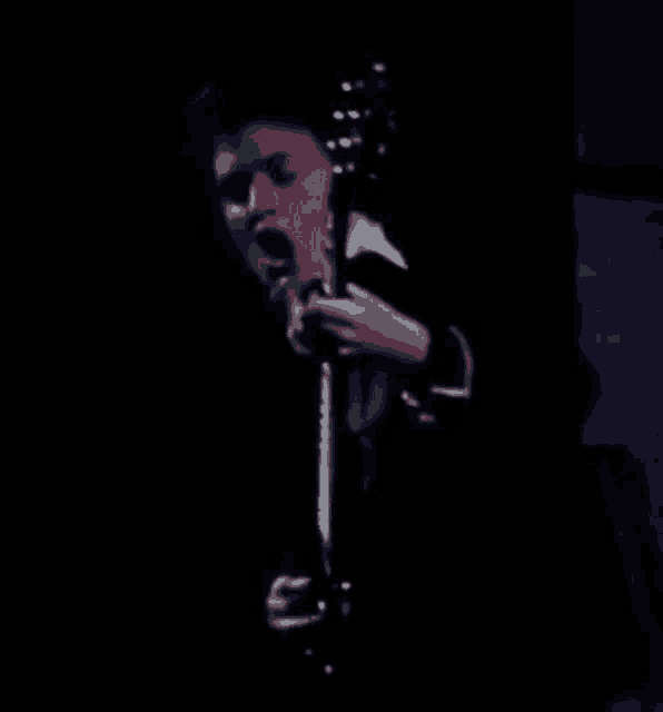 a person is playing a guitar in a dark room