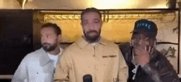 three men are standing next to each other in a room .