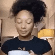 a woman with afro hair is holding a cup of coffee .