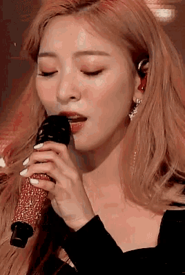 a close up of a woman singing into a microphone with her eyes closed