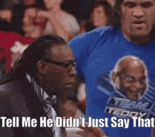 a man in a suit and tie is pointing at another man in a blue shirt .