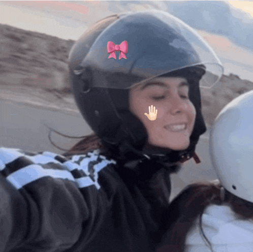 a woman wearing a helmet with a pink bow and a hand on her face
