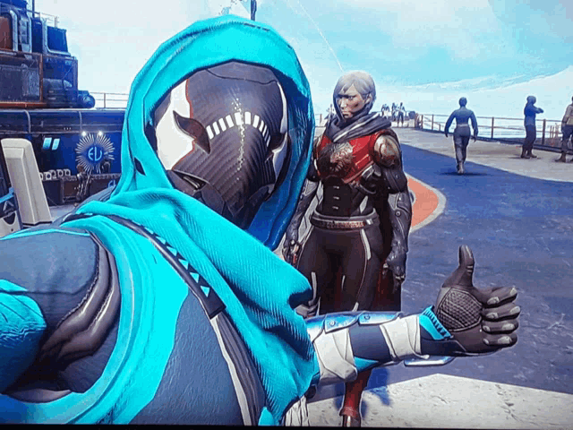 a man in a blue hooded jacket is giving a thumbs up to another man