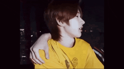 a man in a yellow shirt is being hugged by another man