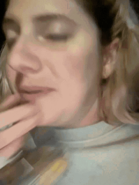 a woman with her eyes closed and her hand on her mouth