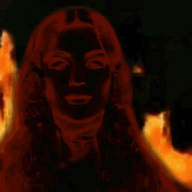 a woman 's face is surrounded by flames in a dark background