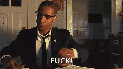 a man in a suit and tie is sitting at a desk with a book and a pen .