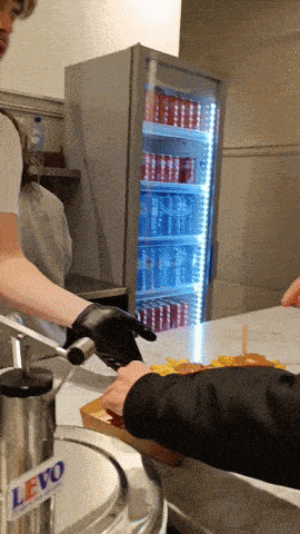 a person wearing black gloves is holding a knife in front of a levo machine