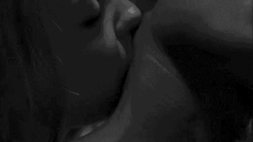 a black and white photo of a man and woman kissing each other .