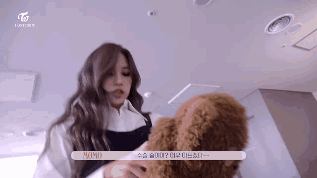 a woman is holding a small brown dog in her arms and talking to it .