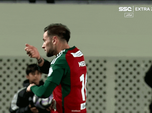 a soccer player wearing a green and red jersey with the number 1 on it