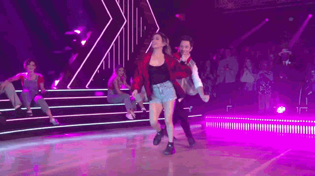 a man and a woman are dancing on a stage in front of a crowd of people .